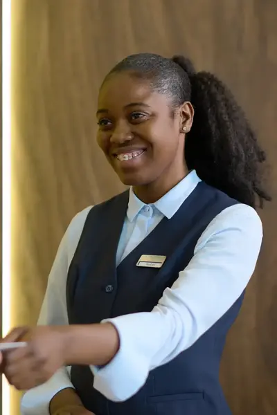 Receptioniste achter hotelbalie geeft keycard af aan hotelgast.