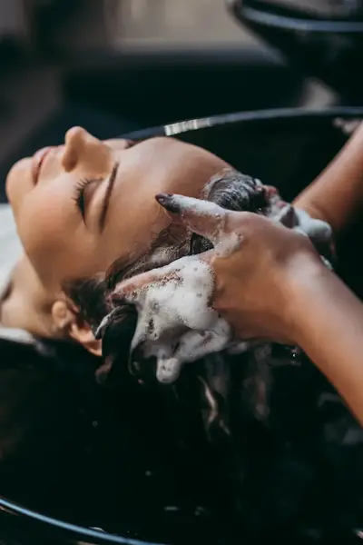 Kapster wast haar klant in wasbak kapsalon. 