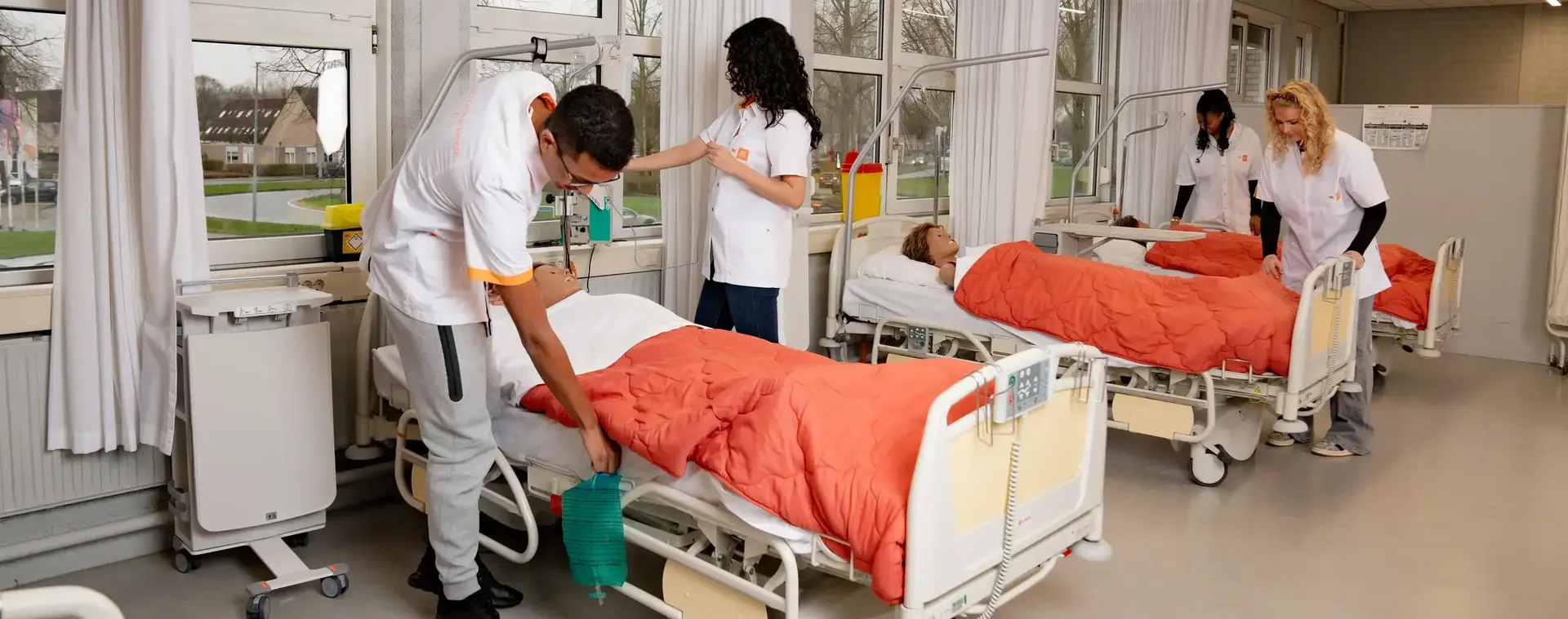 Studenten verpleegkunde met dummypoppen in ziekenhuisopstelling