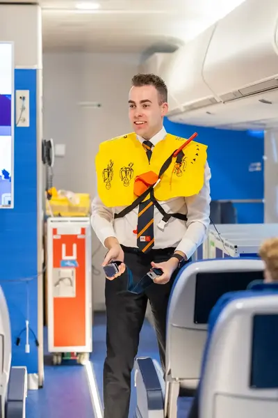 Een steward geeft veiligheidsinstructie aan passagiers.