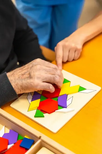 Studente helpt bejaarde man met legpuzzel