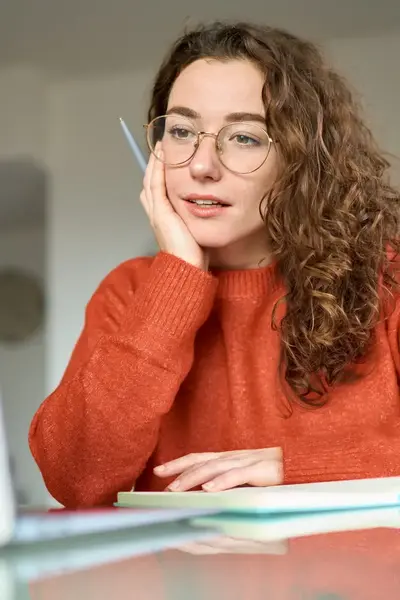 Studente achter haar bureau kijkt dromerig naar haar laptop