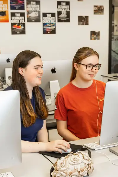 Twee studentes achter één Imac-computer.