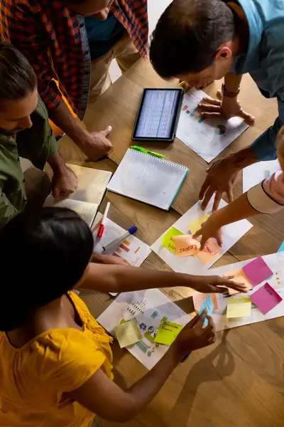Groep studenten aan een ronde tafel in de weer met gekleurde post-its.