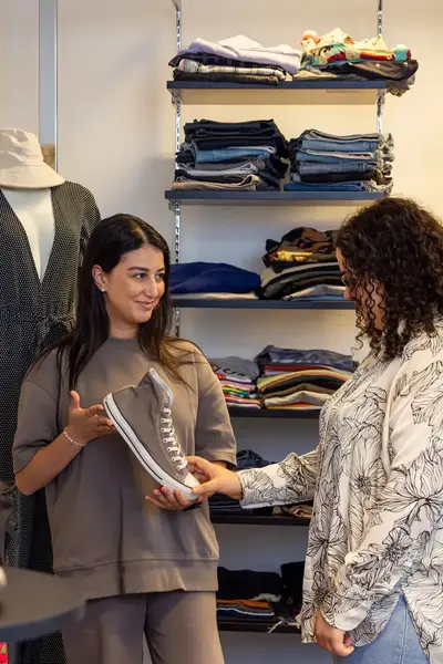 Winkelmedewerkster helpt klant bij het kiezen van schoenen in een kledingwinkel.