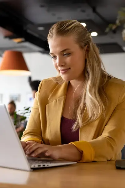 Studente met kop koffie achter laptop.
