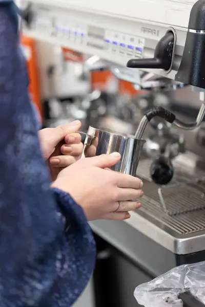 Vrouwenhanden maken melkschuim met een espresso-apparaat.