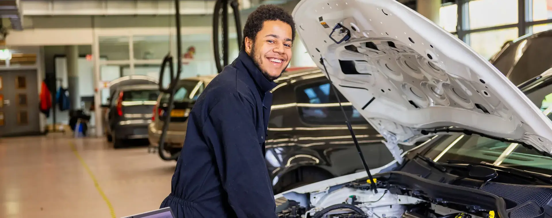 Student helpt met onderhoud aan een auto in de werkplaats