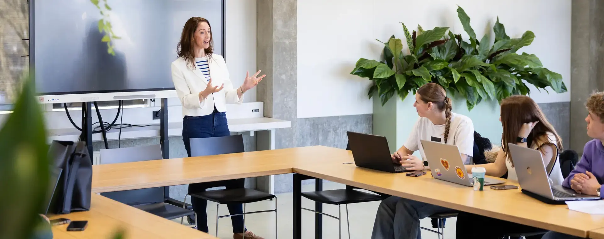 Docent geeft les aan studenten in een klaslokaal met laptops