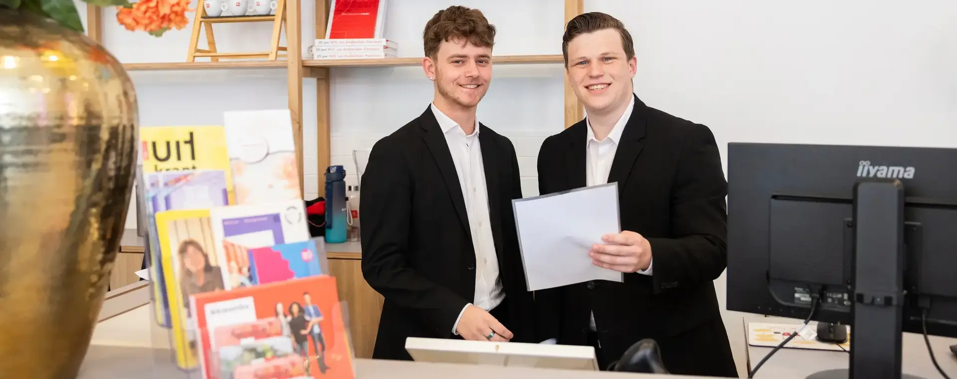 Twee studenten ontvangen gasten bij de hotel receptie