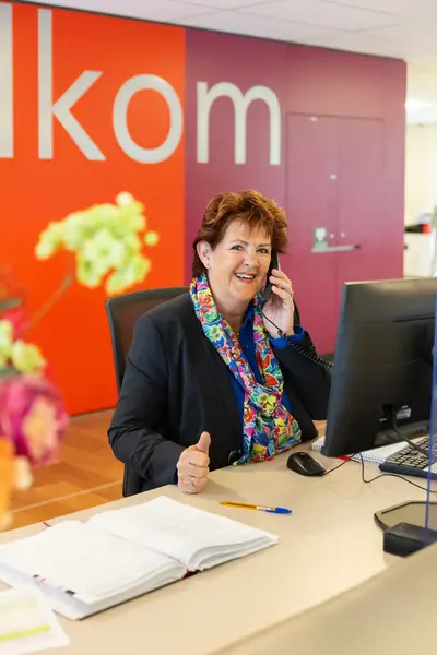 Receptioniste telefoneert achter computerscherm 