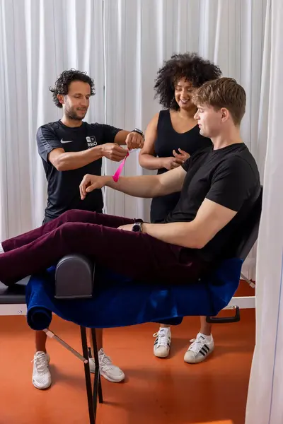 Docent leert studenten hoe ze een arm moeten tapen bij een blessure.