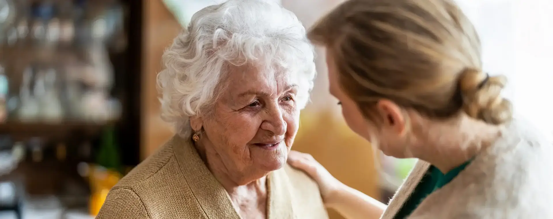 Vrouw houdt haar hand op de schouder van bejaarde vrouw