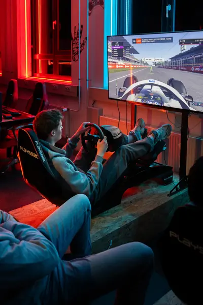 Student zit in een racestoel en is een race game aan het spelen op een groot scherm. 