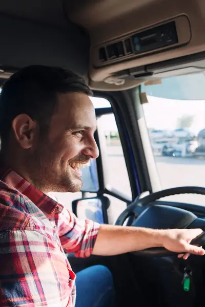 Lachende vrachtwagenchauffeur achter stuur vrachtwagen.